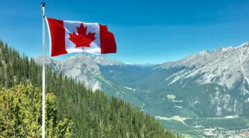 Canadian flag waving over a scenic mountain landscape