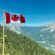 Canadian flag waving over a scenic mountain landscape