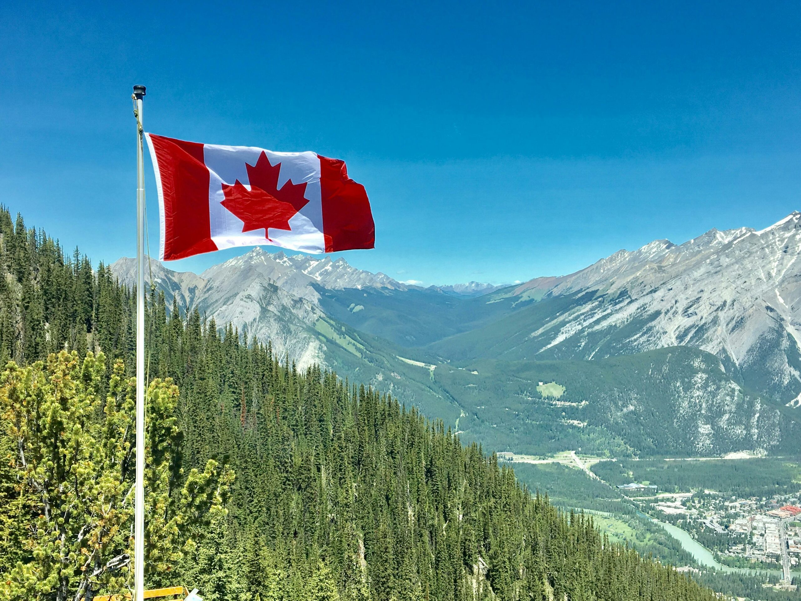 Canadian flag waving over a scenic mountain landscape